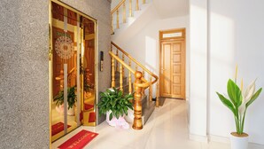 A modern hotel lobby with a staircase, a reception desk, and potted plants. - HANAH HOTEL (Xuan Huong - Da Lat)