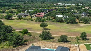 Une vue aérienne d’un quartier résidentiel avec des maisons, des pelouses verdoyantes et un grand champ ouvert.