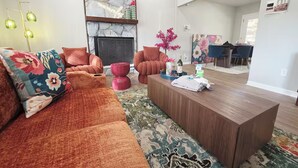 Una sala de estar moderna con chimenea, un comedor y una cocina al fondo.