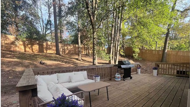 Una terraza de madera con un sofá blanco y una parrilla.