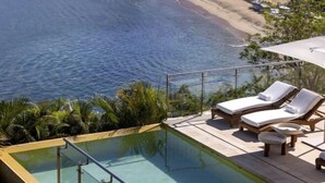Ein Poolbereich mit Liegestühlen und Blick auf den Strand.