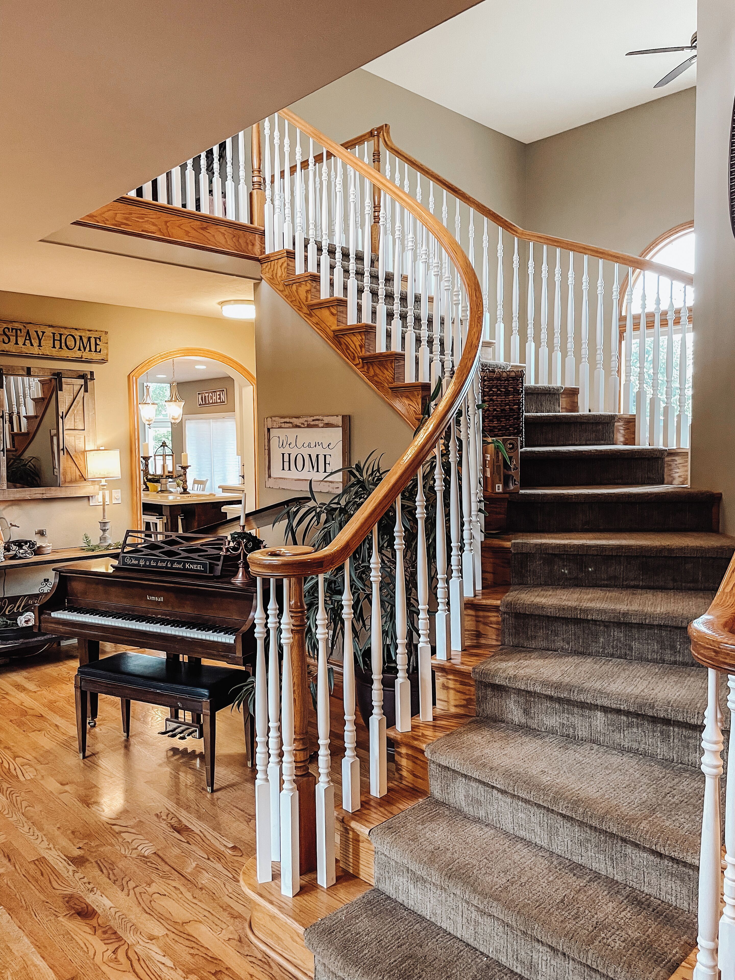 A grand staircase with a spiral design, wooden balusters, and a dark carpeted landing.