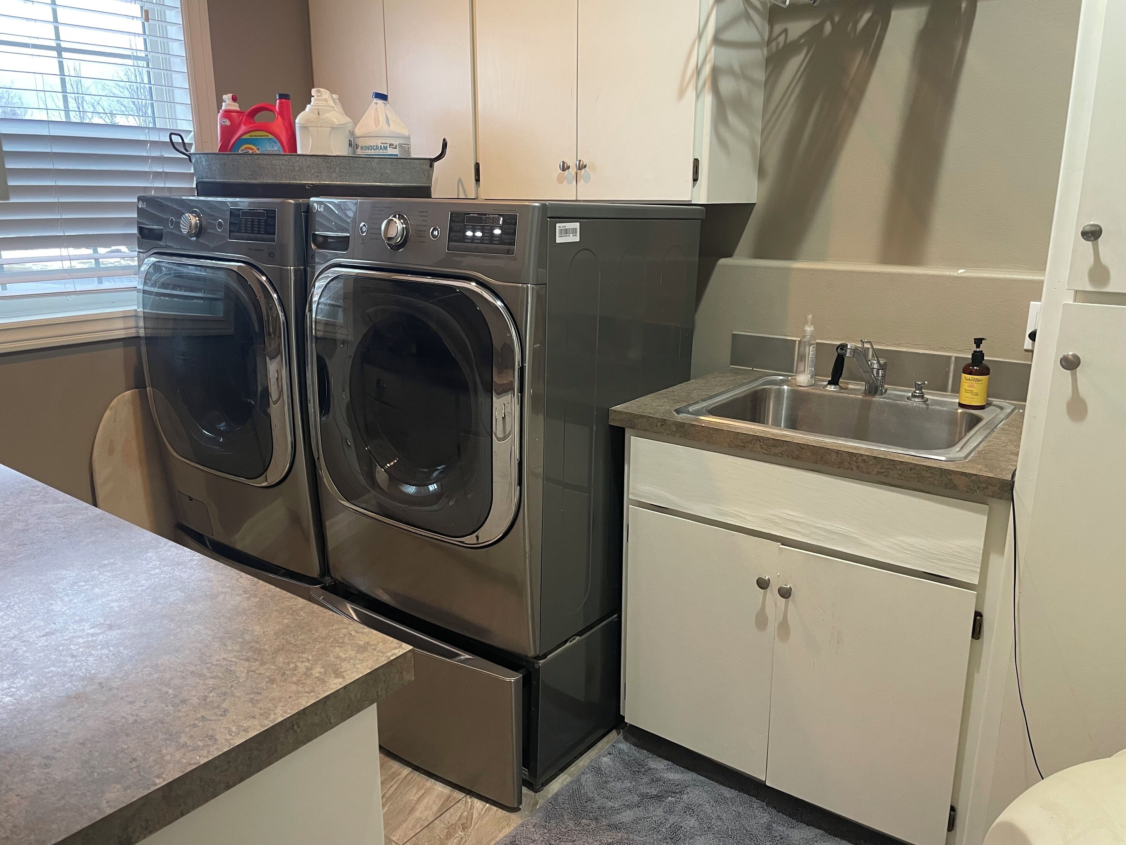 A compact kitchen with a built-in washer and dryer, a sink, and cabinets.