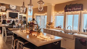Een goed verlichte keuken met een groot kookeiland, barkrukken en feestelijke decoraties.