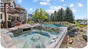 Een achtertuin met een jacuzzi, een zwembad en een overdekt terras met tuinmeubilair.