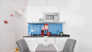 Een moderne keuken met witte kasten, een magnetron, een rode koffiezetapparaat en een blauwe betegelde achterwand.