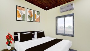 A bedroom with a bed, a nightstand with a vase of flowers, a window, and three framed artworks on the wall. - Super Collection O Srisailam Highway (Hyderabad)