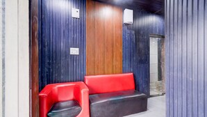A reception area with a red and black bench, wooden paneling, and a blue wall. - Super Collection O Srisailam Highway (Hyderabad)