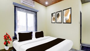 A hotel room with a bed, a window, a wall-mounted air conditioner, and framed artwork. - Super Collection O Srisailam Highway (Hyderabad)