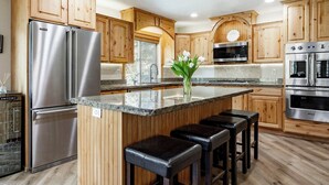 Eine moderne Küche mit Holzausstattung, Edelstahlgeräten und einer Arbeitsplatte aus Granit.