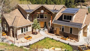 Ein modernes mehrgeschossiges Haus mit Solaranlage, Stein- und Holzelementen und einem gepflegten Garten.