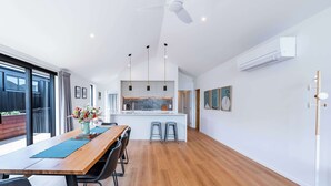 Une cuisine moderne dotée d’un îlot central, de luminaires suspendus et d’un ventilateur de plafond.