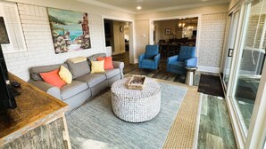 A spacious living room with a grey sofa, blue armchairs, and a round coffee table. - The Lake House at Sunset Bay (Hot Springs)