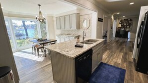 A modern kitchen with a large island, built-in cabinets, and a view of a lake. - The Lake House at Sunset Bay (Hot Springs)