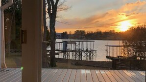 A wooden deck with a view of a lake and dock during sunset. - The Lake House at Sunset Bay (Hot Springs)