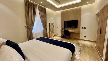 Una habitación de hotel con cama, escritorio, televisor y armario.