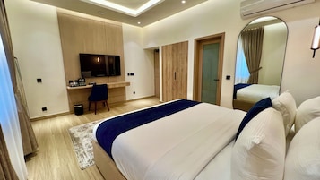 Una habitación de hotel moderna con cama, escritorio, televisor y armario.