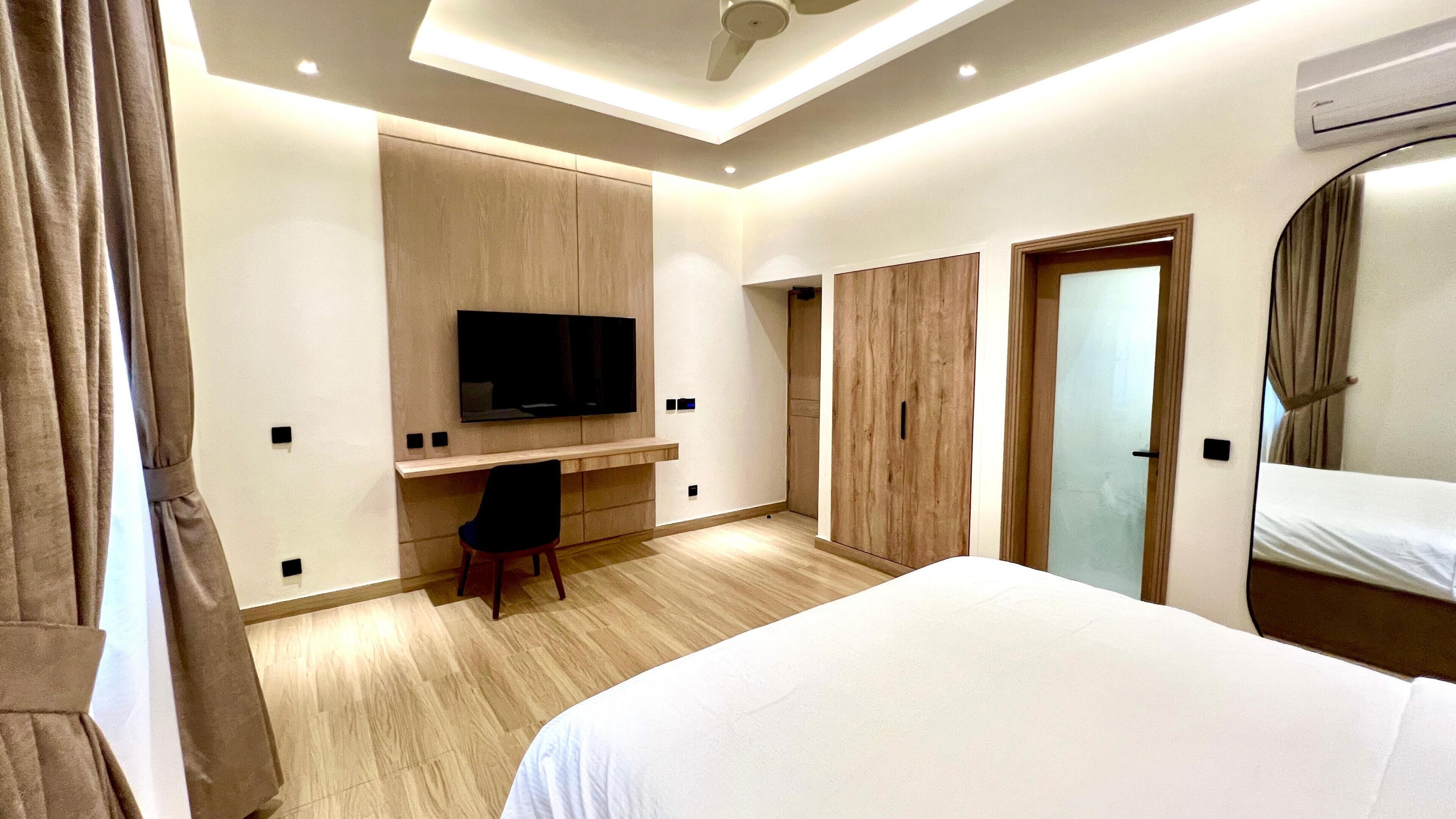 A hotel room with a bed, a desk, a television, and a wardrobe.