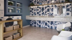 Ein modernes Badezimmer mit Fliesen in geometrischem Muster, einem Holzausleger und einem weißen Stuhl.