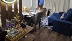 Ein Hotelzimmer mit einem Holztisch, einem runden Spiegel, einem Fernseher, einem Sofa und einem Essbereich.