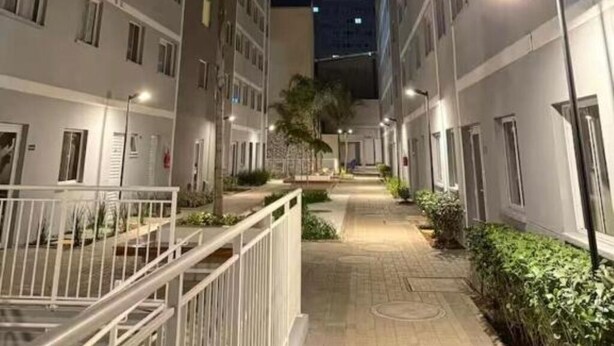 Nachtsicht eines mehrstöckigen Wohnhauses mit Balkonen, einem zentralen Weg und Straßenlaternen.