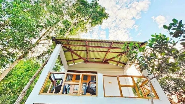 A two-story building with a flat roof and a balcony. - Dolubari Eco Resort Sreemangal (Kamalganj)