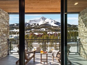 En balkong med utsikt över ett snötäckt berg och en stad nedanför.