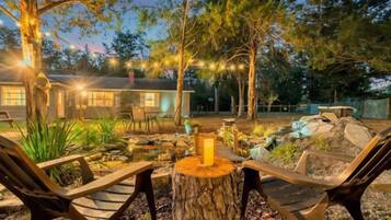 A backyard with a wooden bench, a tree stump, and a house in the background.