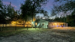 A small, single-story building with a porch and a covered outdoor seating area. - Bnb Hyperion 4B2B Home w Firepit, Hot Tub & Pond (Eustis)