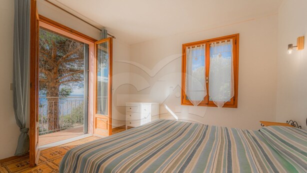 A bedroom with a large bed, a dresser, and a window with curtains.
