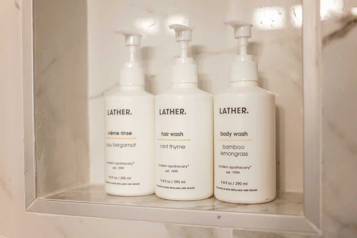 Trois bouteilles de gel douche Lather dans une salle de bain.