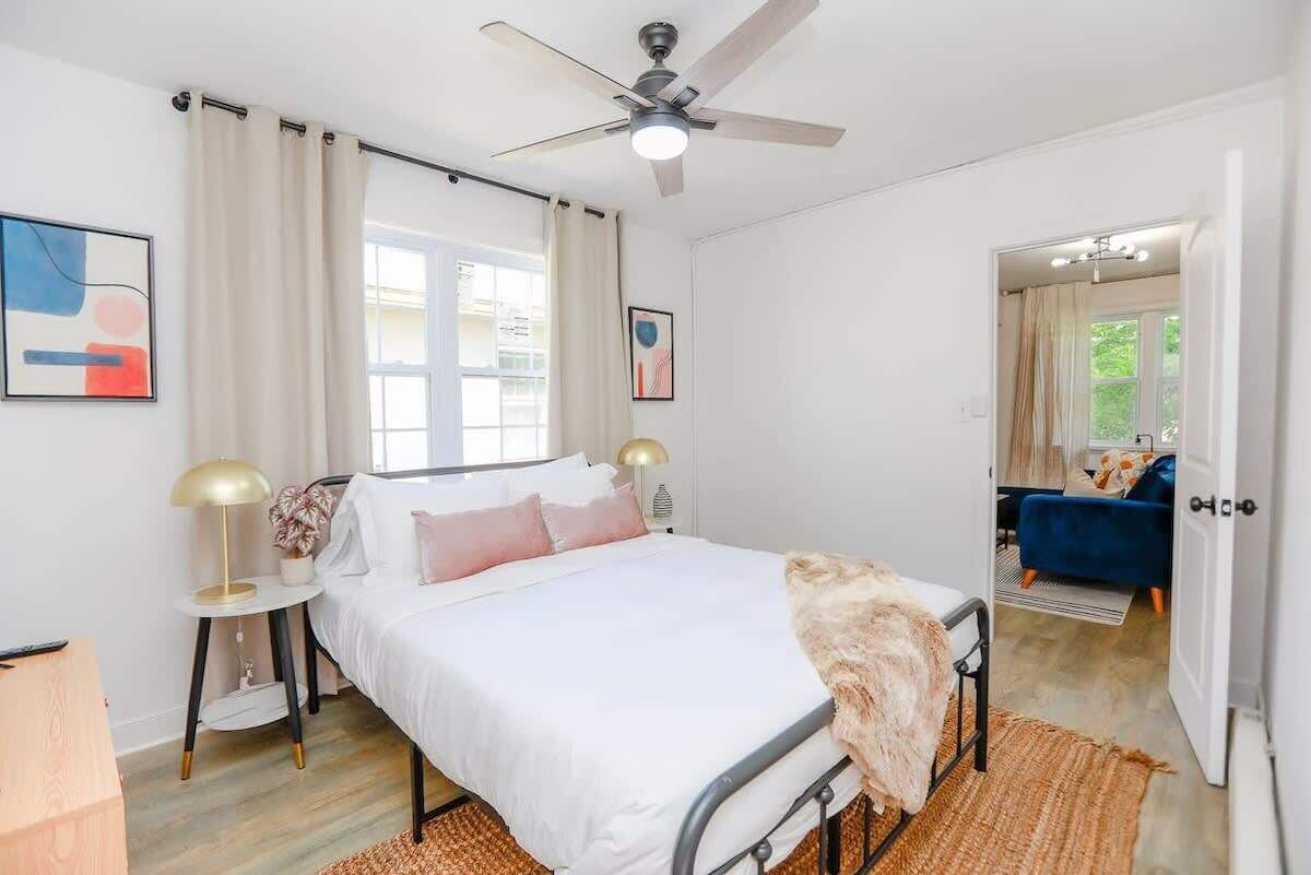 A bedroom with a bed, a ceiling fan, a window, and a door leading to another room.