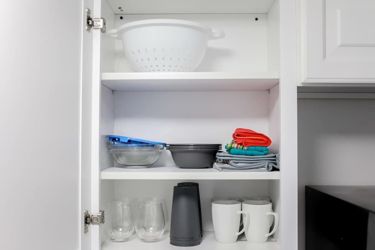 A kitchen cabinet with shelves containing kitchenware.