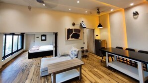 A modern room with a bed, a sofa, a dining table, and a kitchen area.