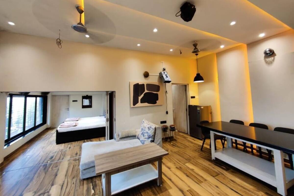 A modern room with a bed, a sofa, a dining table, and a kitchen area.