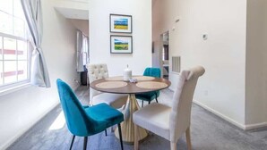 Un comedor con una mesa redonda, cuatro sillas y dos cuadros en la pared.