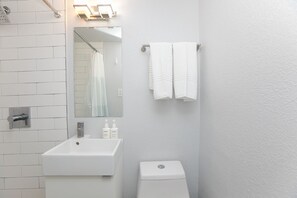 Een badkamer met een wit wastafelmeubel, spiegel en handdoekrek.