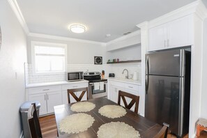Eine moderne Küche mit weißen Schränken, einem Edelstahl-Kühlschrank, einer Mikrowelle und einem Herd.