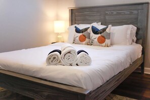 Una cama bien hecha con toallas enrolladas y almohadones en una habitación de hotel.