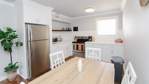 Una cucina moderna con mobili bianchi, elettrodomestici in acciaio inossidabile e un tavolo da pranzo in legno.