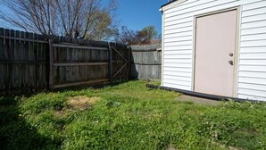 A fenced backyard with a shed and a door. - Sojourn | Virginia Beach | 2 Bedroom Townhouse (Virginia Beach)
