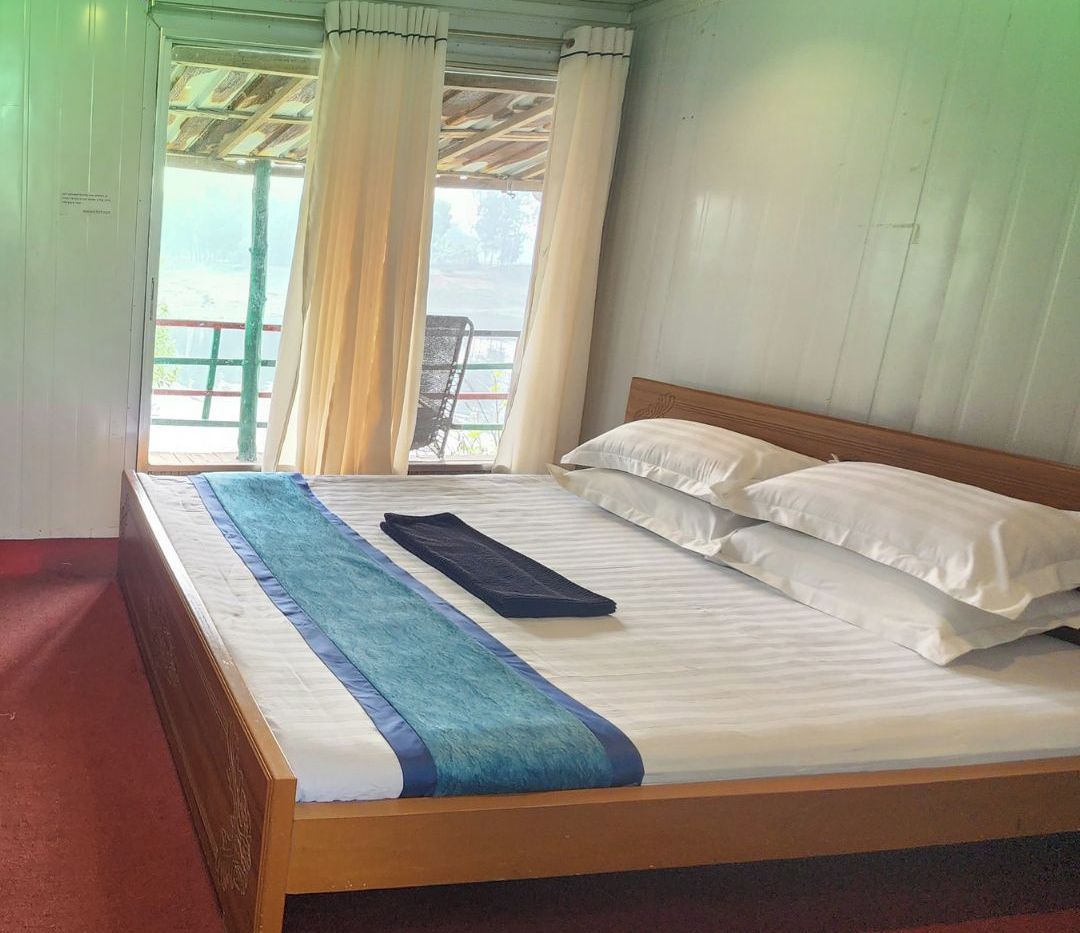 A single-bed room with a wooden headboard, white bedding, and a view of a balcony with a chair.