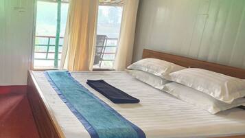 A single-bed room with a wooden headboard, white bedding, and a view of a balcony with a chair.