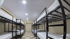 A dormitory room with bunk beds arranged in two rows, a checkered floor, and a ceiling with recessed lighting. - Vista Inn Patong (Patong)