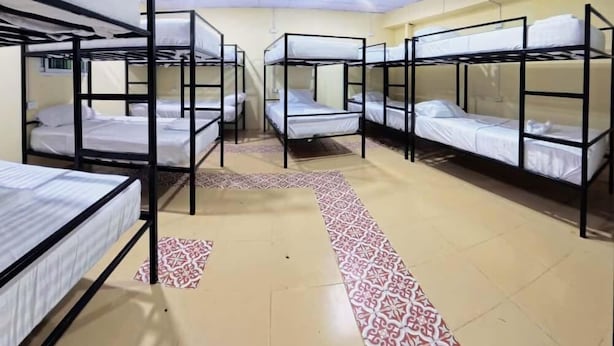 A dormitory room with bunk beds arranged in two rows, a patterned carpet, and a tiled floor. - Vista Inn Patong (Patong)