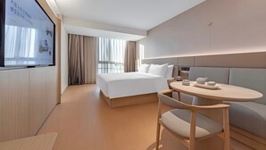 Una habitación de hotel moderna con cama, mesita de noche y una pantalla grande en la pared.