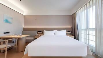 A modern hotel room with a large bed, a desk, and a chair.