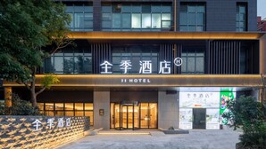 Un hotel con fachada moderna, amplios ventanales y una entrada destacada con puerta giratoria.