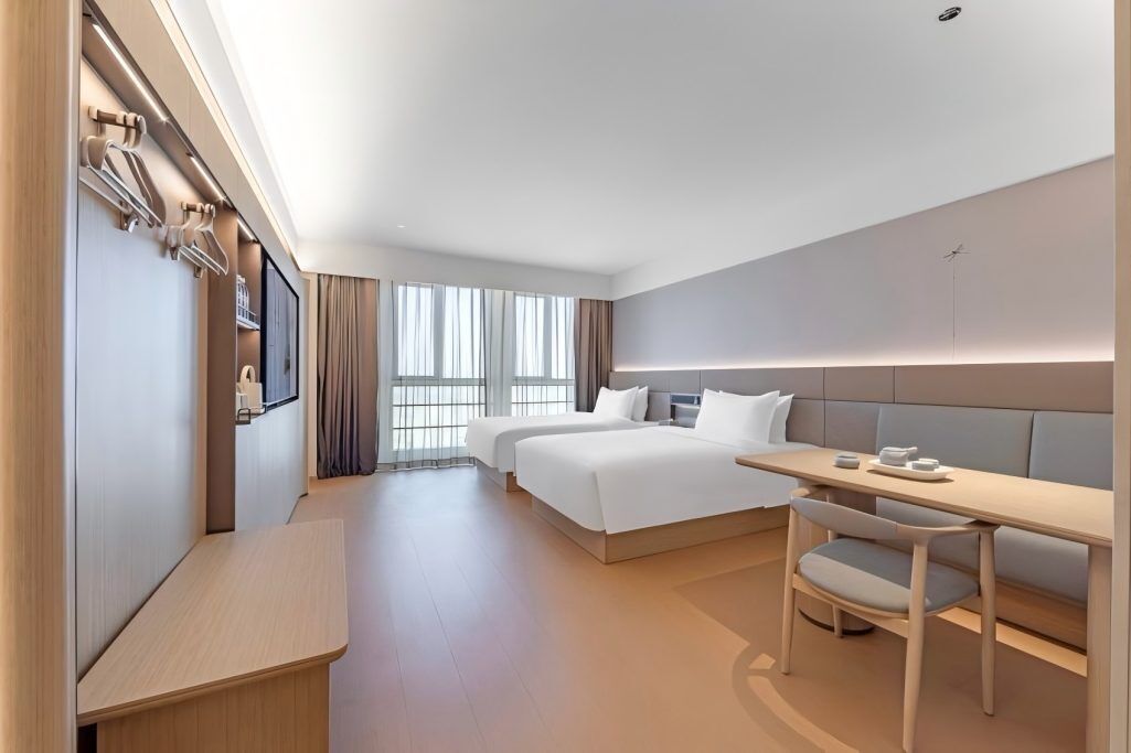 A hotel room with a bed, a desk, a chair, and a wardrobe.