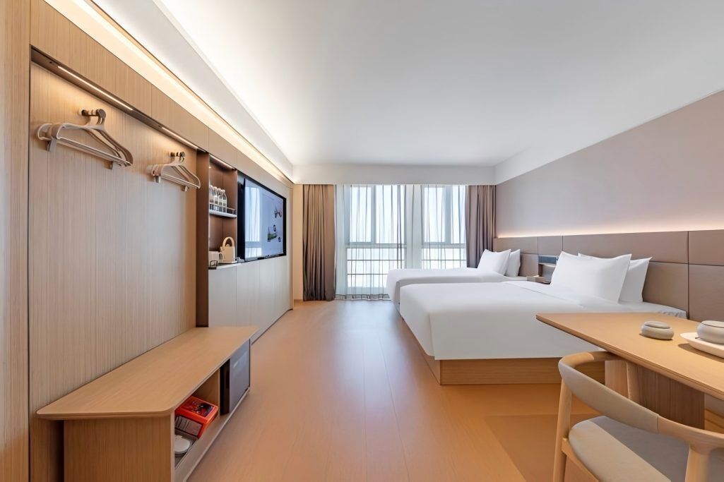 A hotel room with a bed, bedside table, TV, and a seating area.